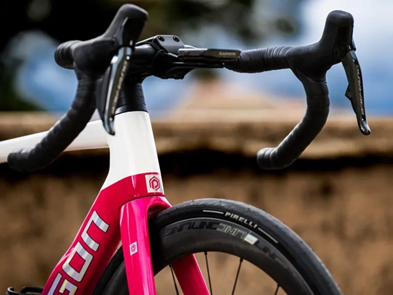 Bicycle tire on smooth tarmac transitioning to a rough gravel road surface.