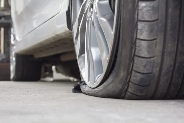 A damaged car tire with a crushed sidewall showing signs of severe wear.