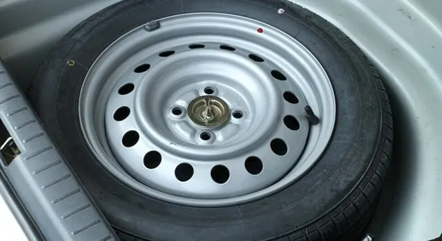 A disorganized trunk with a jack and spare tire illustrating common weight reduction errors.