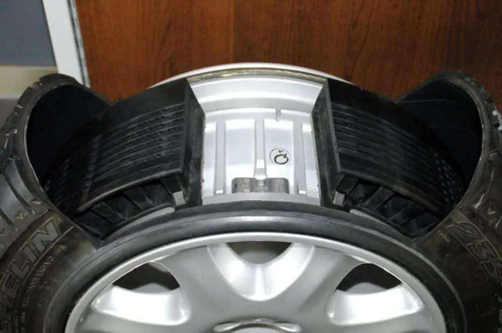 A person using a pressure gauge to check tire air pressure on a wheel.